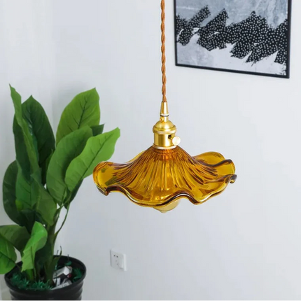 Suspension vintage en verre ondulé ambré et laiton suspendue près d'une plante verte dans un salon clair