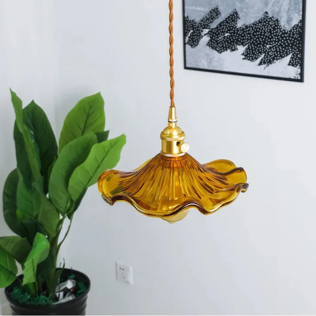 Suspension vintage en verre ondulé ambré et laiton suspendue près d'une plante verte dans un salon clair