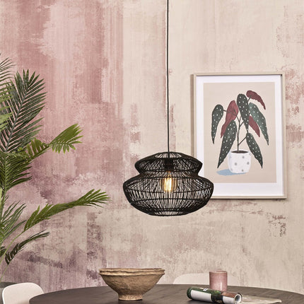 Suspension Zanzibar en rotin tressé noir dans un intérieur aux tons roses avec plantes et objets déco