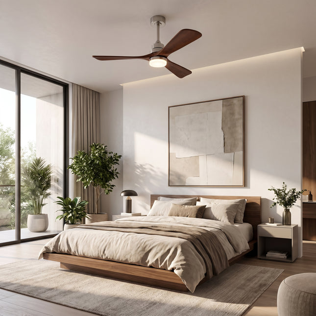 Ventilateur de plafond à trois pales en bois massif de noyer et structure argentée, allumé dans une chambre neutre et lumineuse