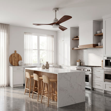Ventilateur de plafond à pales en bois massif de noyer et structure argentée, au-dessus d'un îlot de cuisine en marbre blanc
