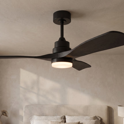 Ventilateur de plafond noir mat allumé au-dessus d'un lit, lumière blanche chaude dans une chambre beige