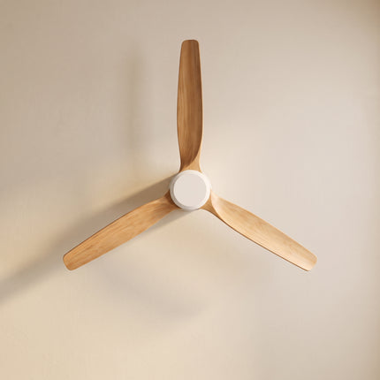 Vue de dessous des trois pales en bois clair et du moyeu blanc du ventilateur de plafond