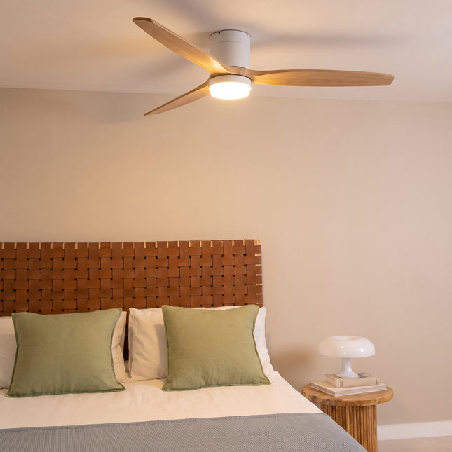 Ventilateur de plafond bas LED bois clair et blanc allumé au plafond d'une chambre chaleureuse
