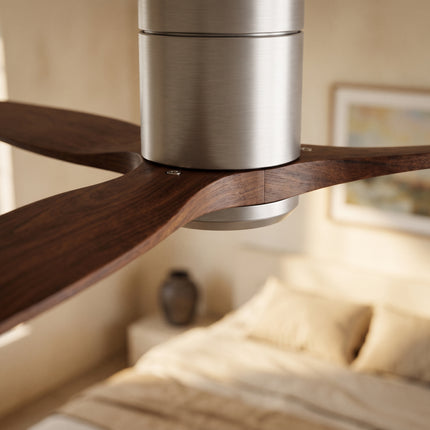 Gros plan sur une pale en bois noyer et le moyeu argent brossé du ventilateur de plafond