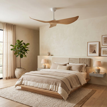 Ventilateur de plafond blanc à pales effet bois clair installé dans une chambre beige aux tons lin