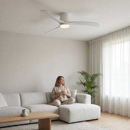 Ventilateur de plafond flush mount blanc intégral LED allumée au-dessus d'une femme dans un salon japandi