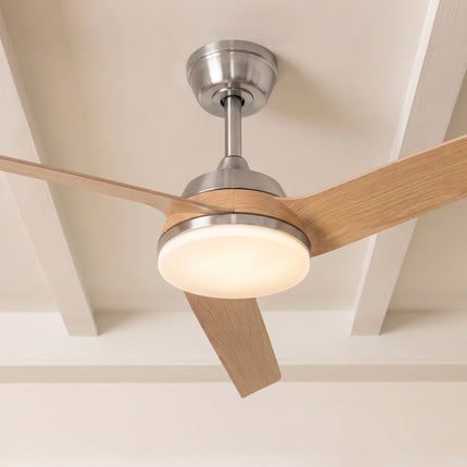 Vue rapprochée du ventilateur de plafond allumé, ses trois pales bois clair et son diffuseur LED blanc chaud